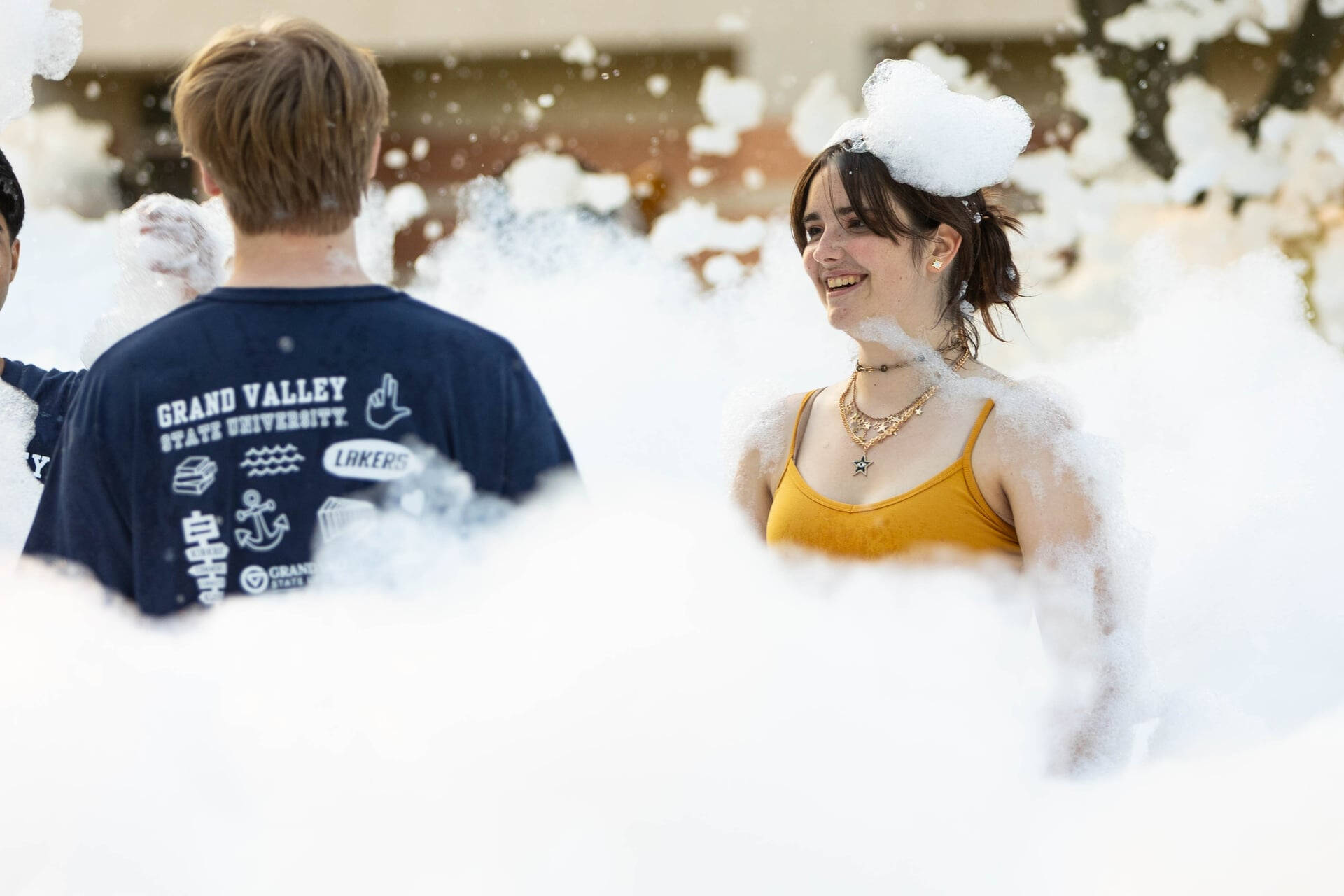 two students smile while standing in the foam pit during Laker Kickoff